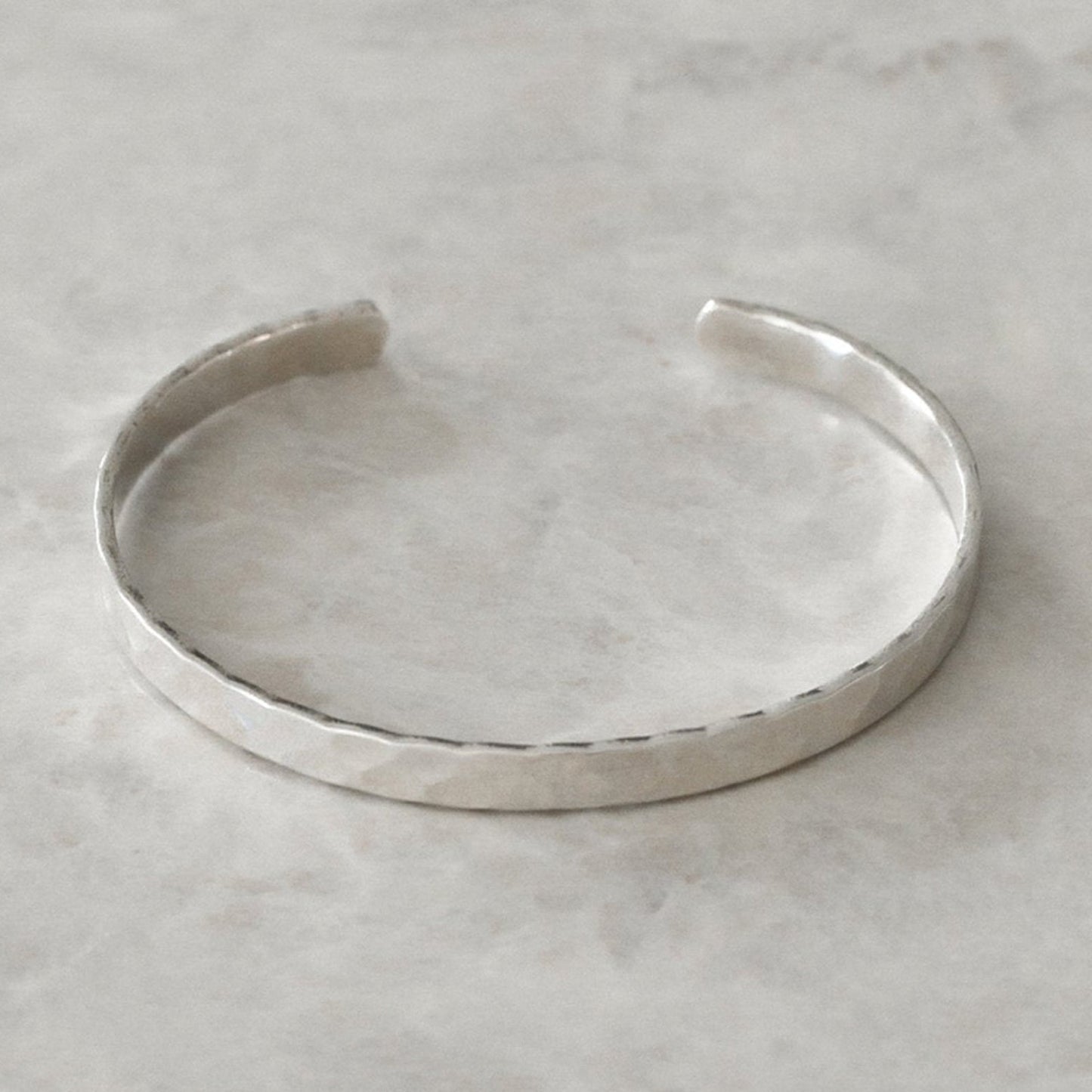 Silver cuff bracelet on a light gray background