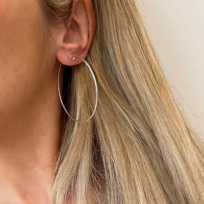 Side view of a model wearing a large 50mm 925 sterling silver fine hoop earring to show size and scale